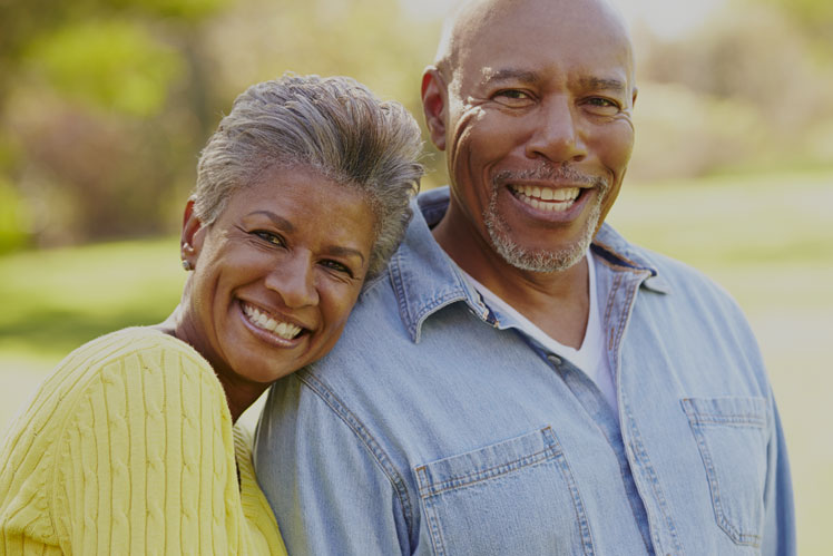 Happy elderly Black couple smiling brightly outdoors.